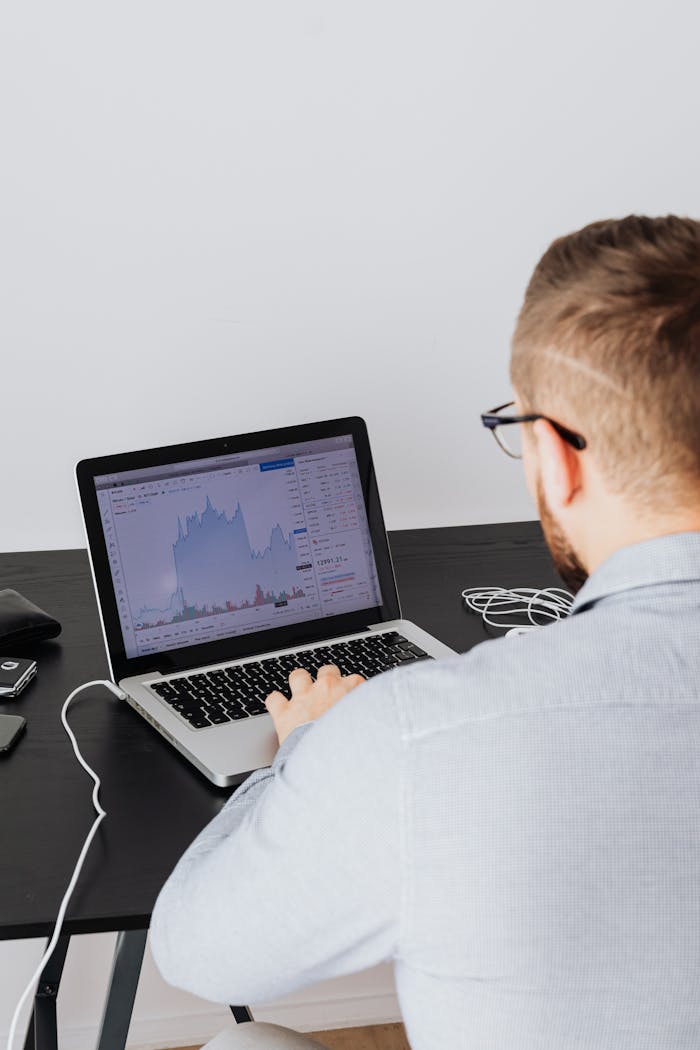 our-services-3 Adult man analyzing cryptocurrency data on laptop at indoor desk.
